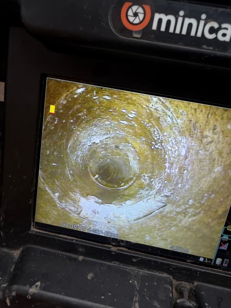 CCTV view of a damaged drain pipe with heavy scale and buildup before lining